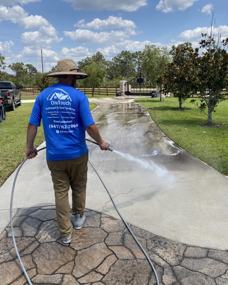 Brett Horton, owner of One Touch Softwash & Paver Cleaning applying cleaning solution to a walkway.