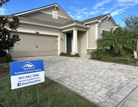 Image with of One Touch Softwash & Paver Cleaners business sign in front a recently cleaned residence.